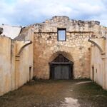abandoned stone structure with an archway leading to a door