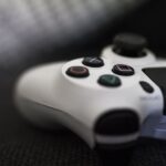 Close-up of a white game controller with colorful buttons on a dark surface.