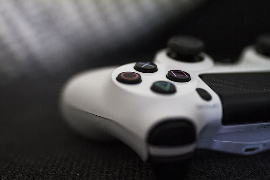 Close-up of a white game controller with colorful buttons on a dark surface.